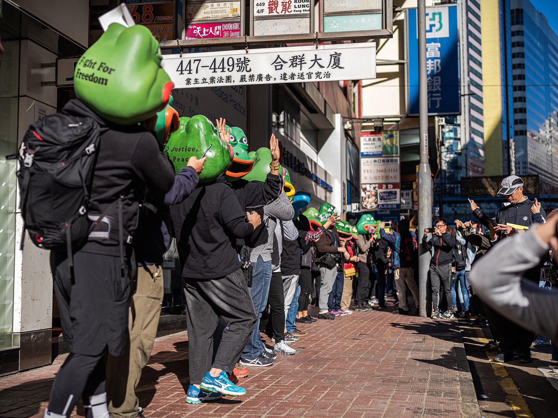 Pepe masks at a pro-democracy march in Hong Kong, 8 December 2019 — a use of the character with the opposite political valence to the American one, adopted independently and welcomed by Furie. Photo: Studio Incendo, CC BY 2.0, via Wikimedia Commons.